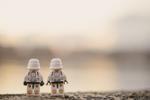 Two Lego minifigures standing close to each other and looking off into the distance.