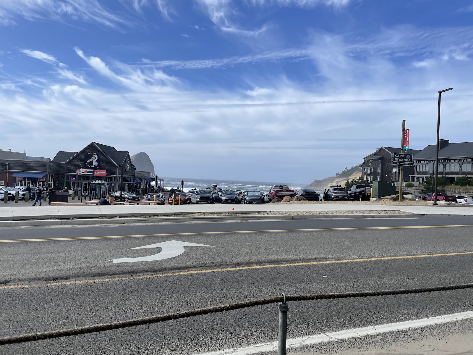 Sitting down on the pavement while an obscured view of the ocean is off in the distance.