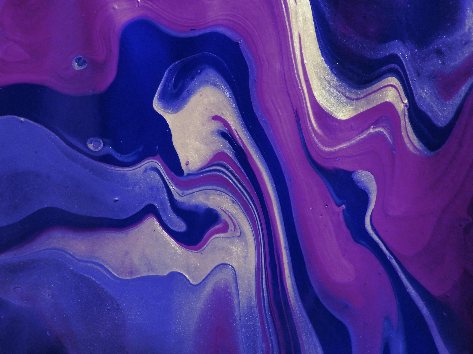 Abstract art of purple and blue liquids mixing together to create new shapes and ripples.