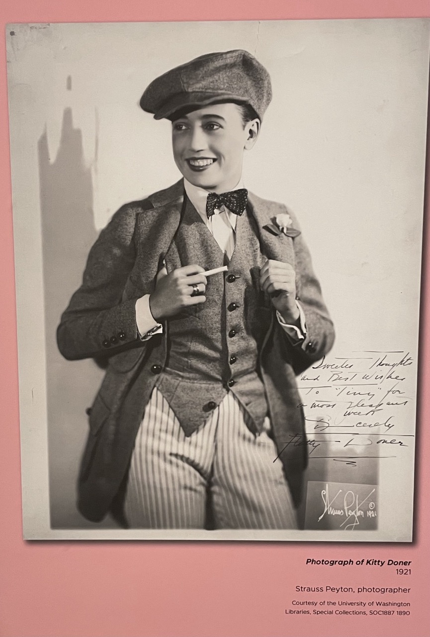 Kitty Doner is pictured in 1921 wearing attire men's attire including a three piece suit, bow tie, and a flat cap.
